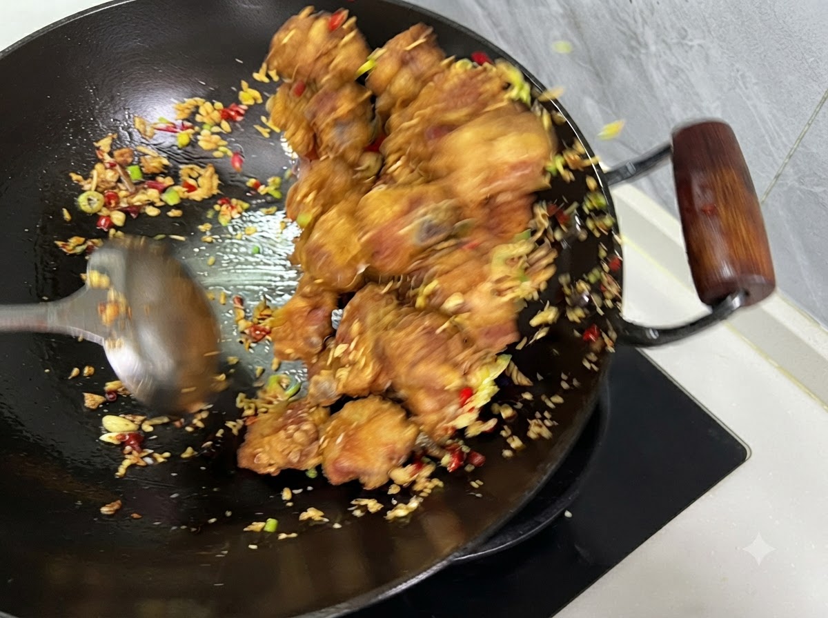 Żeberka, papryczki chili i czosnek mieszane razem chochelką w woku.