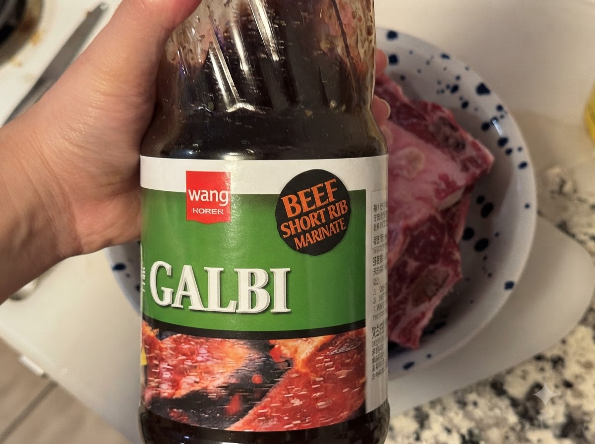 Butelka koreańskiego sosu BBQ Galbi wlewana do miski zawierającej surowe żeberka.
