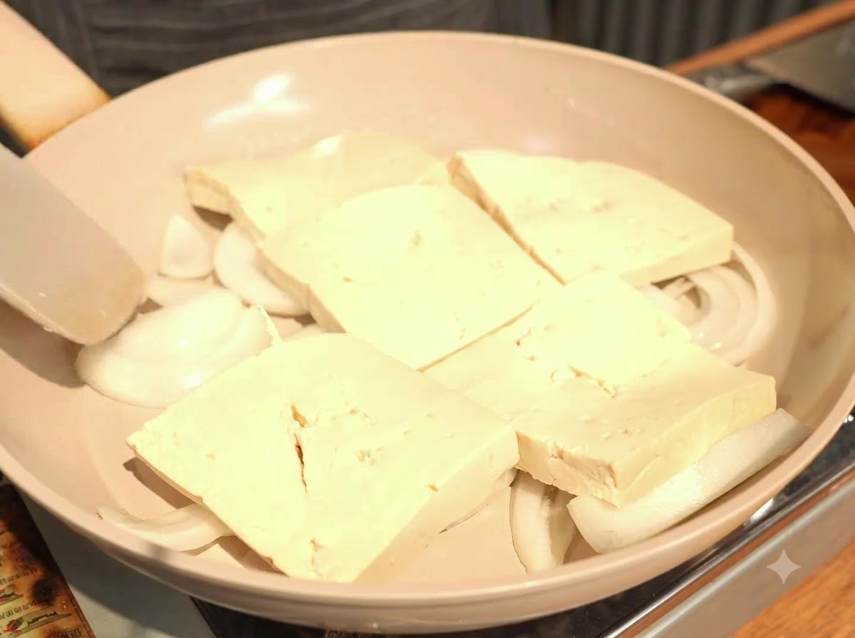 Układanie grubych plastrów tofu w pojedynczej, lekko zachodzącej na siebie warstwie na cebuli.