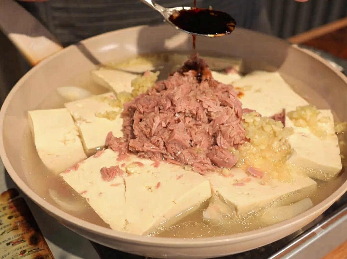 Ciemny sos sojowy skraplany łyżką na środek kawałków tuńczyka i tofu.