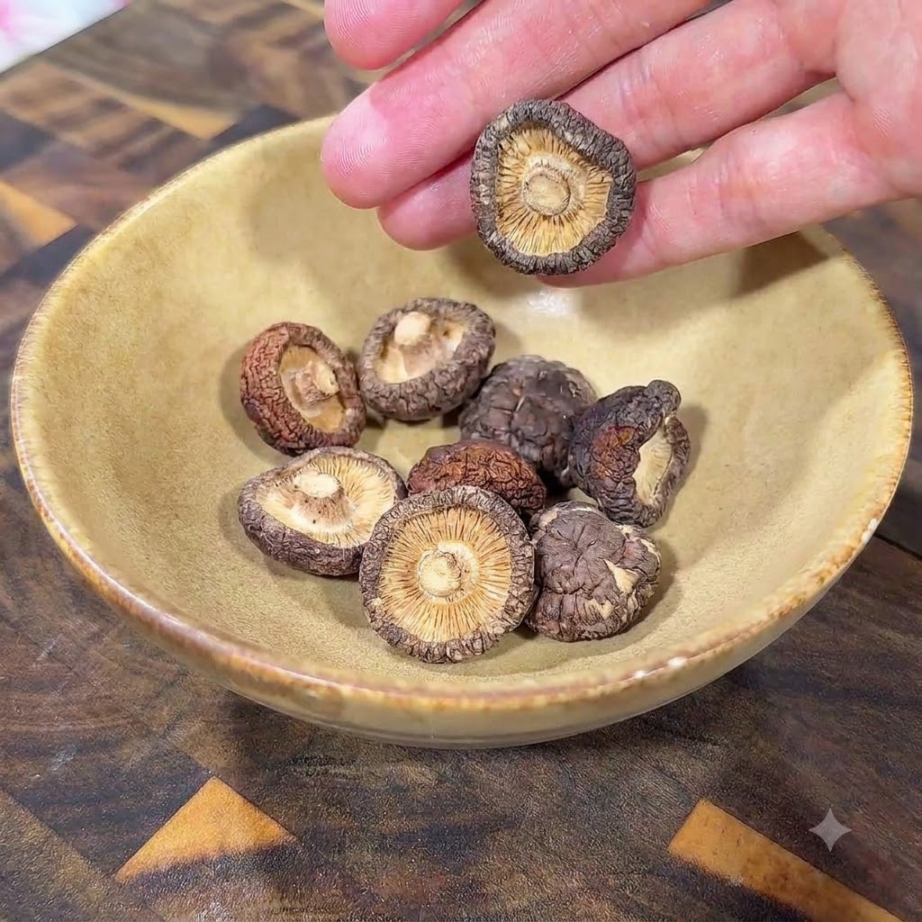 Suszone grzyby shiitake w żółtej ceramicznej misce na drewnianej powierzchni.