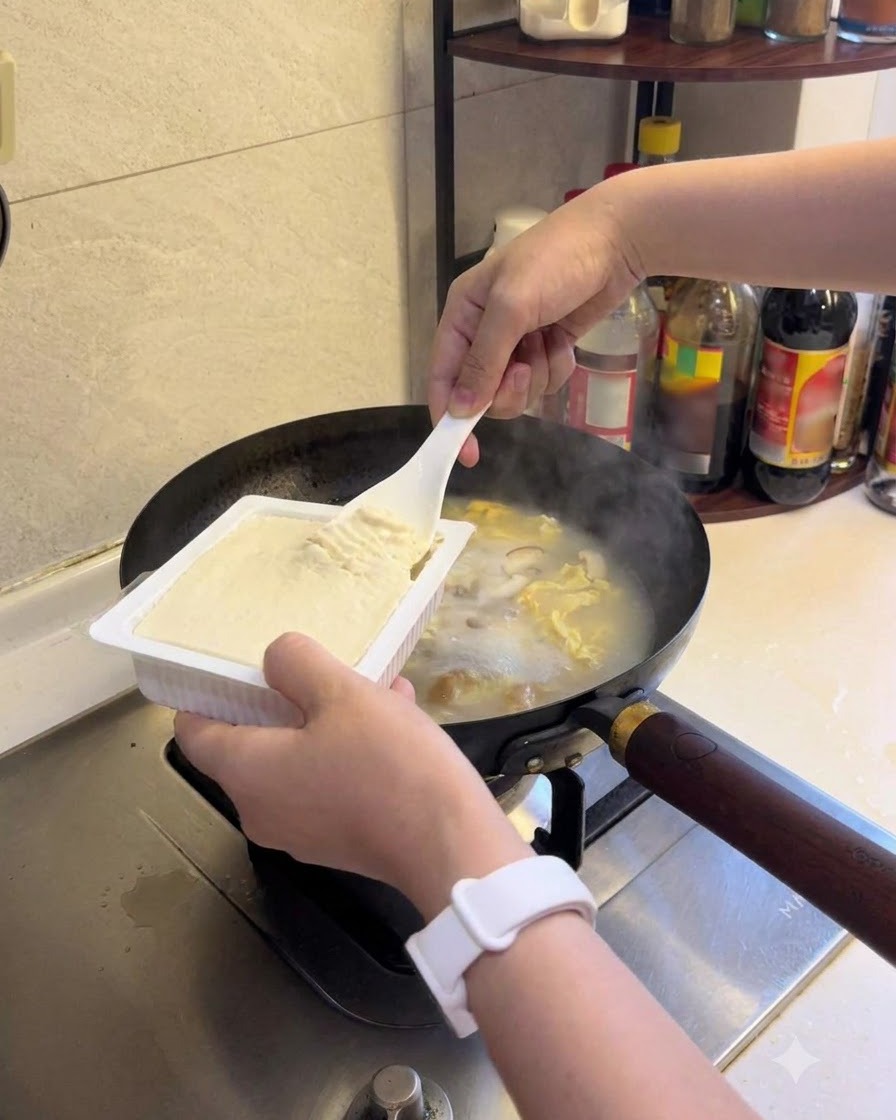 Miękkie tofu dodawane do gotującej się na wolnym ogniu zupy.