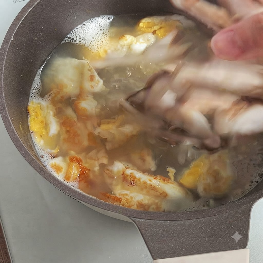 Ręka wrzucająca pokrojone świeże grzyby shiitake do gotującego się bulionu z kawałkami smażonego jajka.