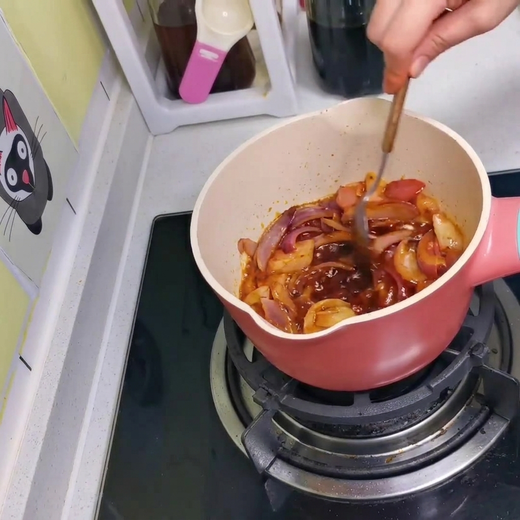 Sos, cebula i kimchi mieszane razem w garnku za pomocą łyżki.
