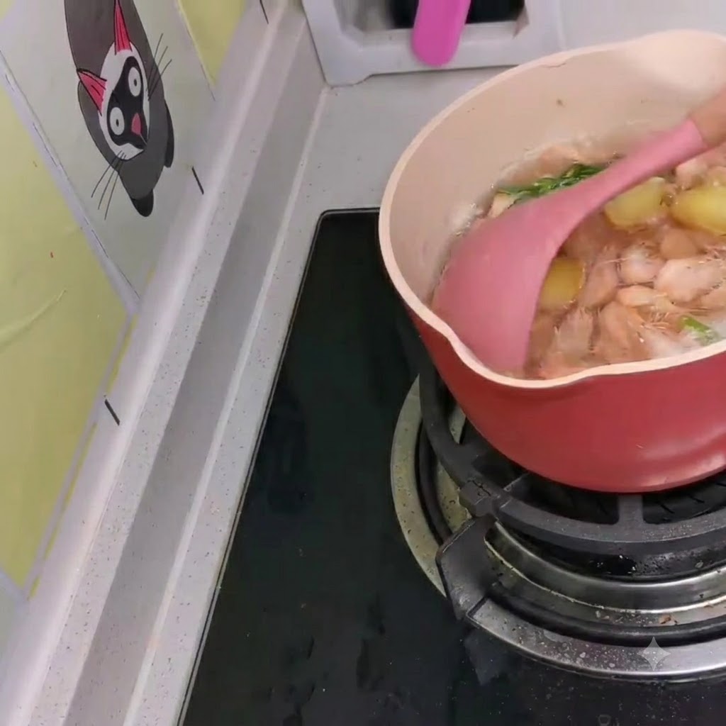 Małe białe krewetki wplatane do gotującego się koreańskiego ramenu za pomocą różowej łopatki.