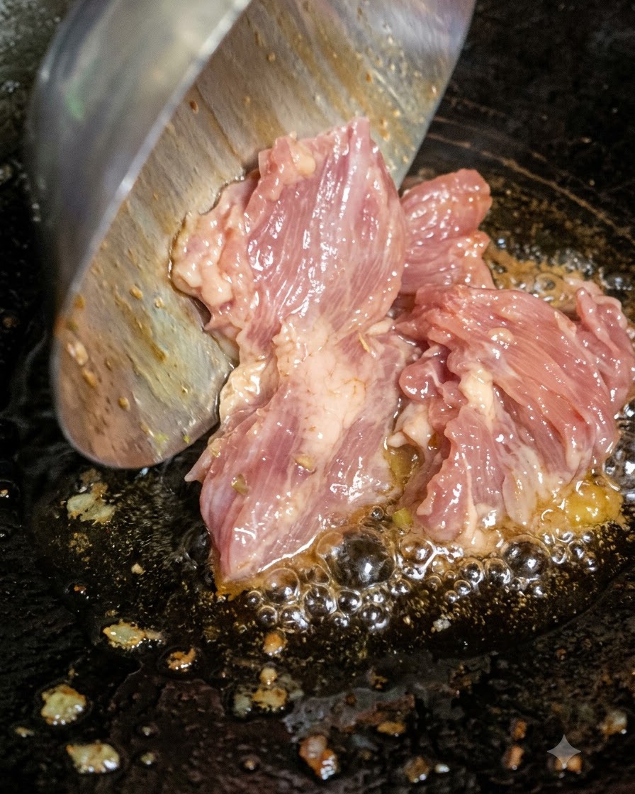 Surowe posiekane mięso dodawane za pomocą łopatki do gorącego, bulgoczącego oleju w woku.
