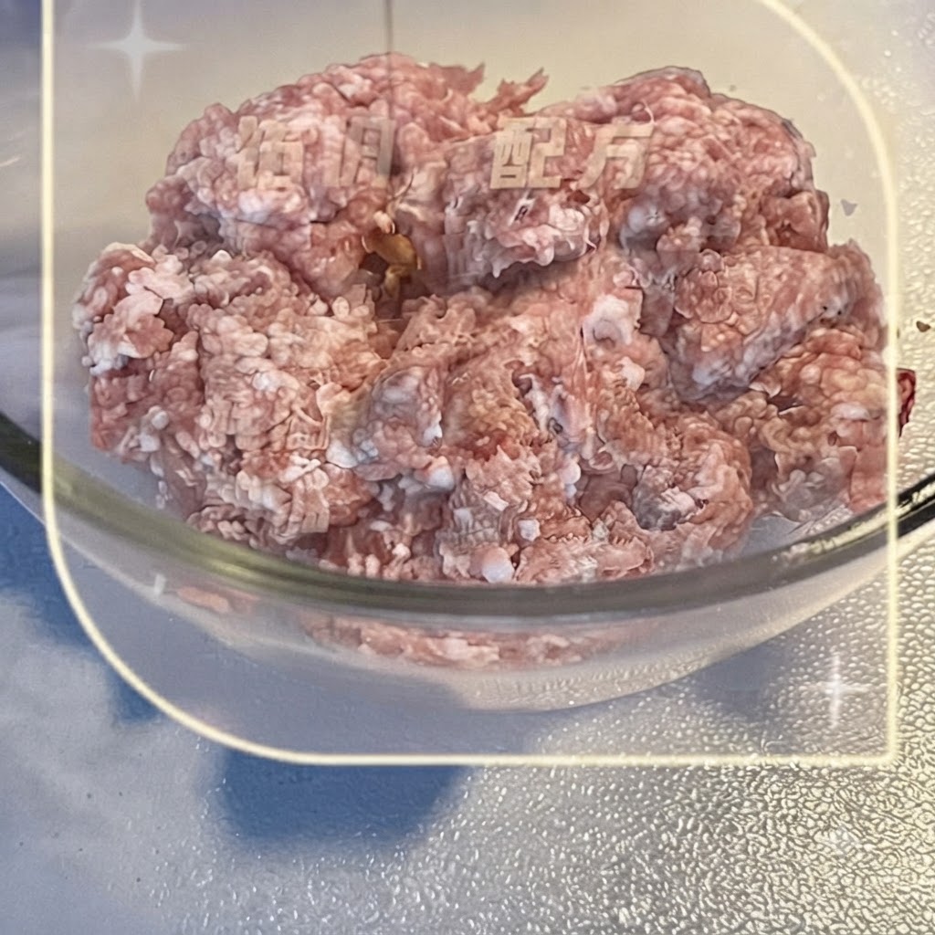 Mielone mięso wieprzowe w przezroczystej szklanej misce mieszane z płynnymi przyprawami.