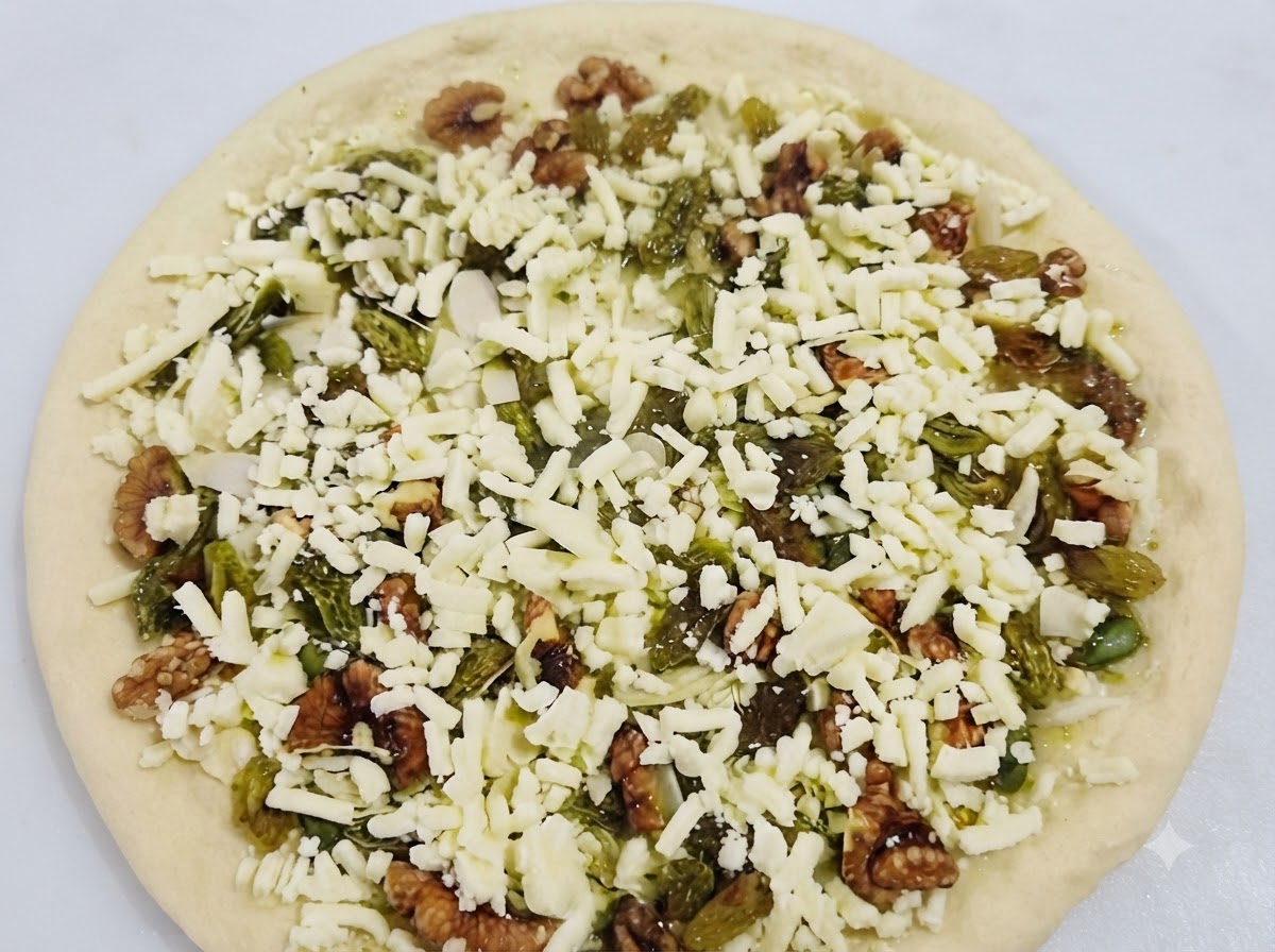 W pełni złożona słodka pizza pokryta serem, orzechami i rodzynkami gotowa do pieczenia.